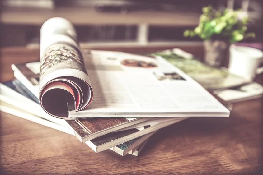 Zwinięty magazyn na stosie czasopism, na drewnianym stole